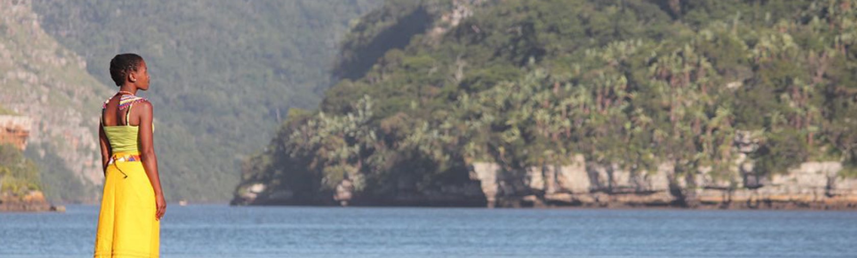 Woman in yellow gazes out across water 