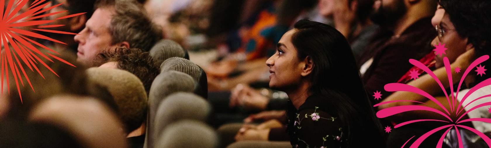 Indoor cinema audience members looking towards the screen with firework graphics overlaying the image.