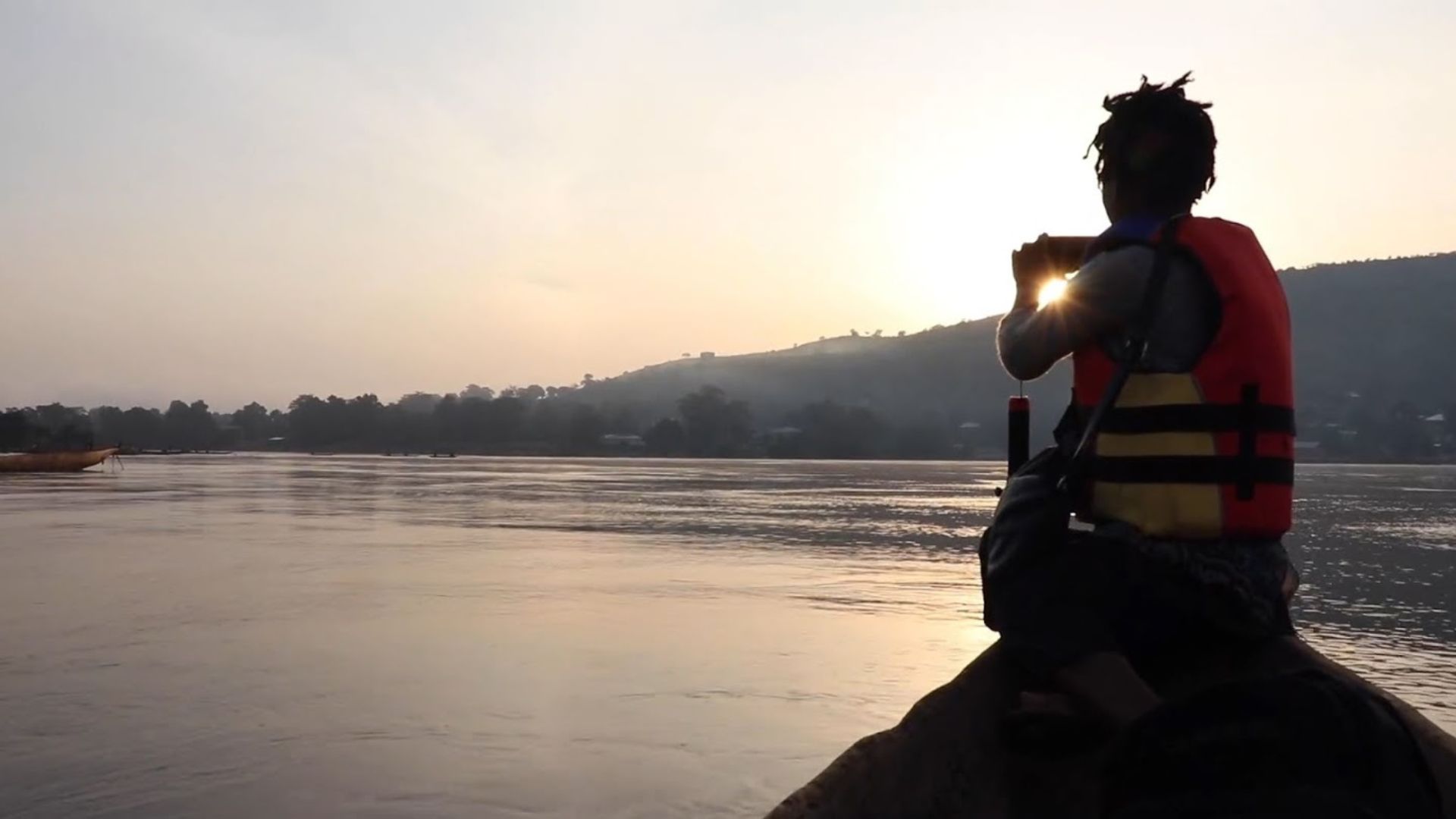 A person sits at the bow of a canoe overlooking calm waters