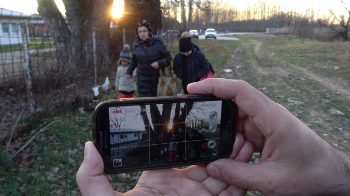 Person taking a photo of a woman walking with kids