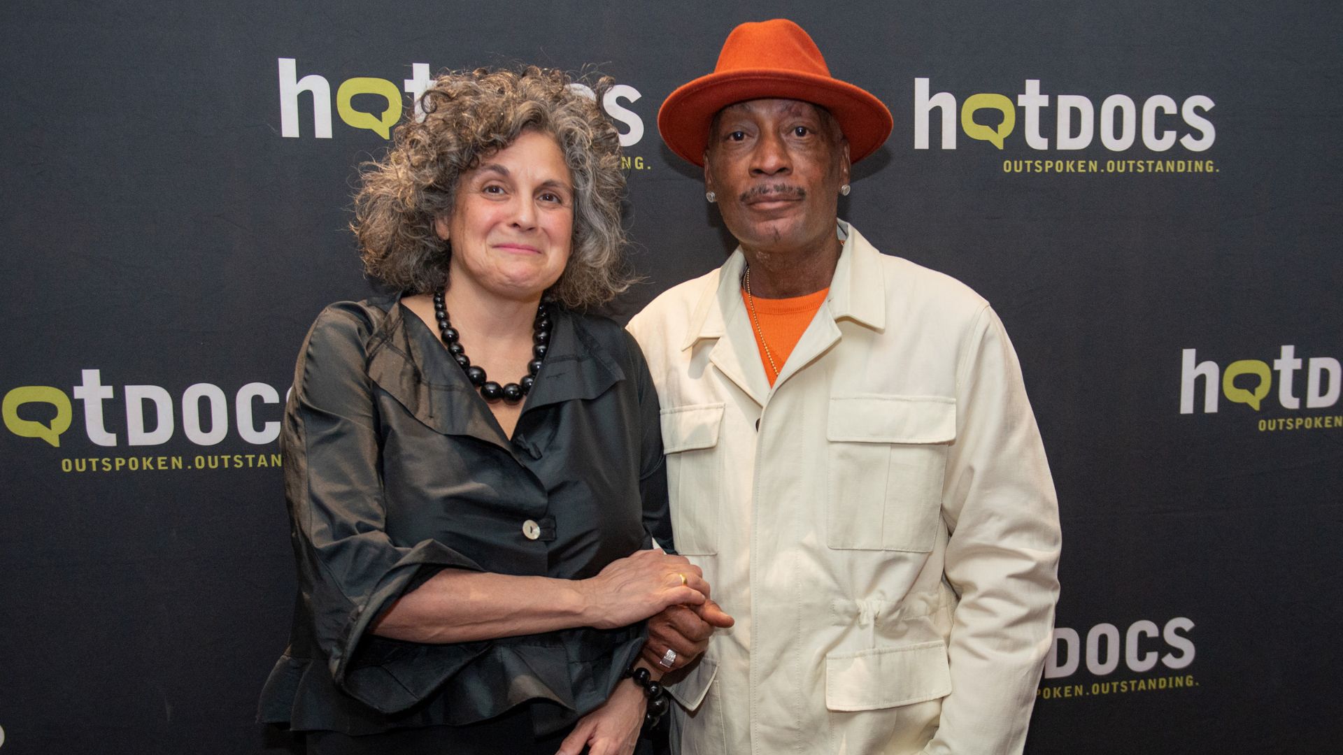 Jennifer Baichwal and Dewayne Johnson in front of a Hot Docs logo backdrop.