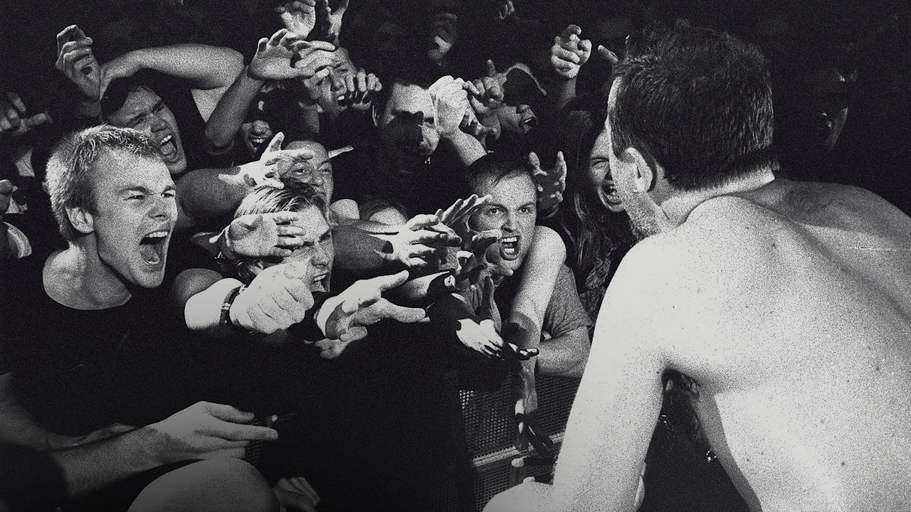 Black and white image of Metallica fans screaming and reaching towards the singer on-stage.